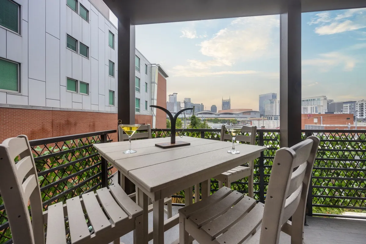 A stylish rooftop terrace with a table set with drinks, ample outdoor seating, and panoramic views of the Nashville skyline—a perfect spot for celebrating, unwinding, or capturing group selfies at sunset.