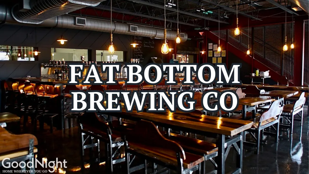 This interior image features long communal wooden tables, industrial lighting, a bar area, and a decorative wall. The setting is lively and social, suggesting a venue perfect for craft brew tasting, live music, or gathering with friends.